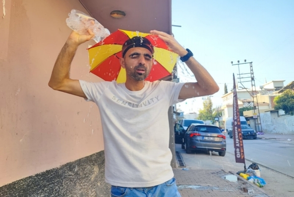 Kafasına taktığı şemsiye ile geziyor